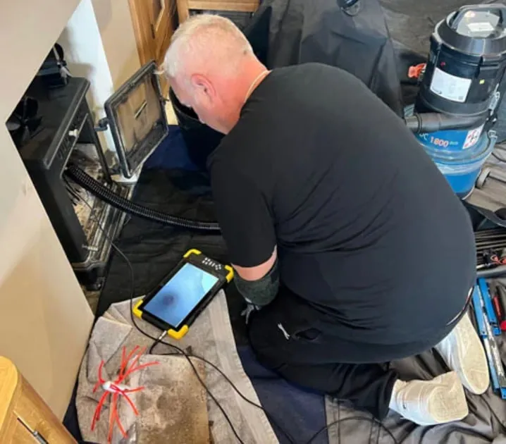 Chimney sweep watching a CCTV screen showing the inside of a flue