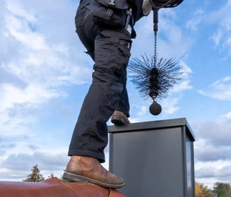 Chimney sweep standing on a roof, lowering a weighted brush down a chimney